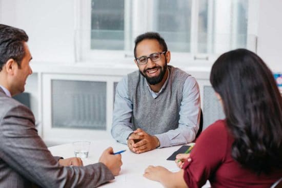 a man sitting and smiling at his colleagues
