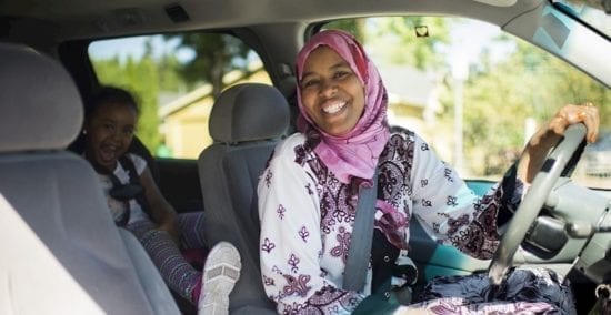 smiling woman driver with child in back seat